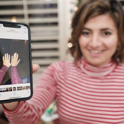 Belle Barbu, at home in Washington, Washington County, on Tuesday, Dec. 3, 2019, shows a photograph on her phone taken when she met her of some of her biological family in Italy that shows her hand alongside her sister’s hand.