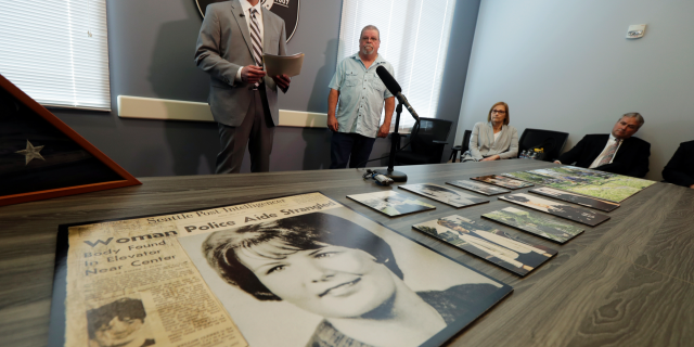 Seattle Police homicide Detective Rolf Norton, left, talks to reporters near a photo of Susan Galvin, who was murdered in Seattle in 1967. (AP Photo/Ted S. Warren)