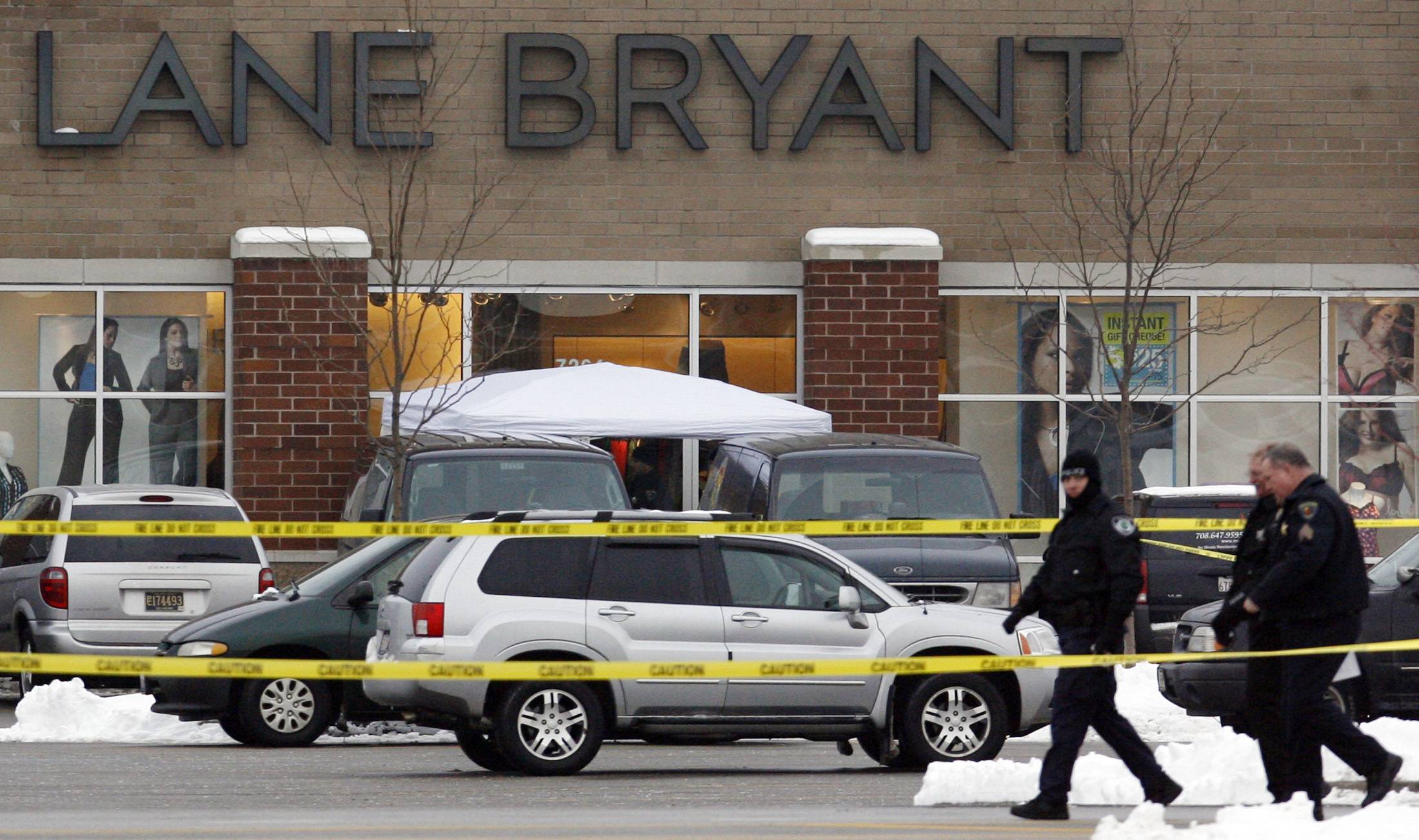 Police walk outside a Lane Bryant store at a shopping center in Tinley Park, investigating the scene in 2008 where five women were killed during a robbery. The case remains unsolved.